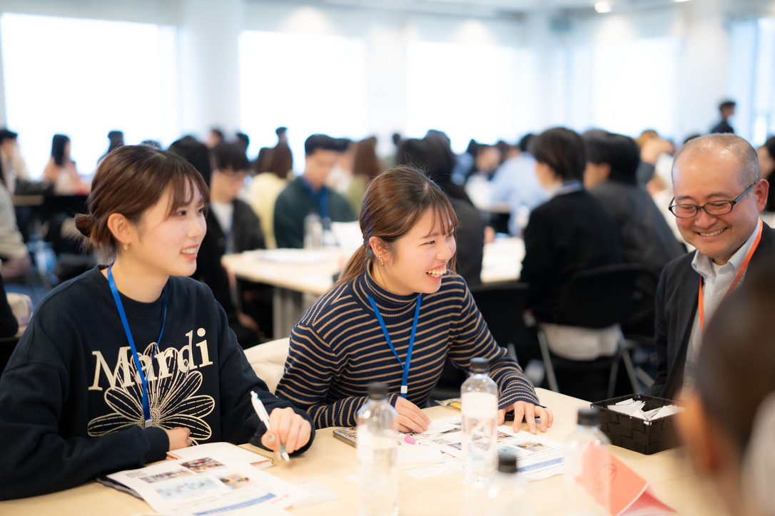 企業の方と学生が笑顔で対話する交流座談会の様子